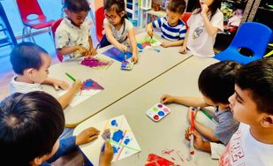 Toddlers engaged in hands-on learning at Level Up Montessori, painting with brushes and colors, building early skills.