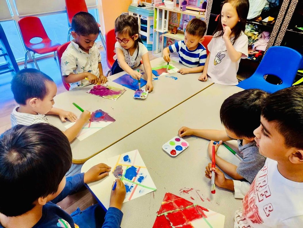 Toddlers engaged in hands-on learning at Level Up Montessori, painting with brushes and colors, building early skills.
