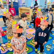 Toddlers at Level Up Montessori enjoying hands-on learning and play, wearing festive arts and crafts hats.