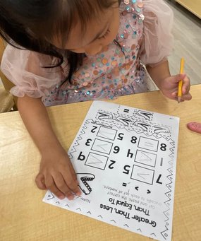 Child developing early academic skills with a math worksheet at Level Up Montessori.