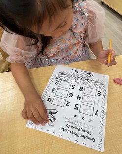Child developing early academic skills with a math worksheet at Level Up Montessori.