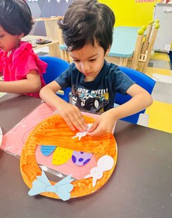 Child engaging in a Montessori craft activity, enhancing confidence and early academic skills for kindergarten readiness.