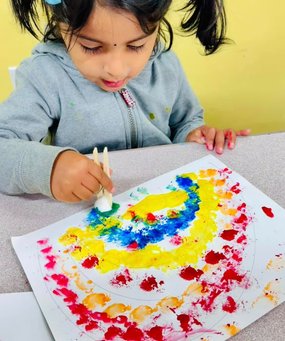 Toddler engaged in painting at Level Up Montessori, enhancing early skills through hands-on learning and play.