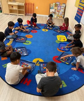 Children engaging in hands-on learning at Level Up Montessori preschool, sitting in a circle working on academic activities.