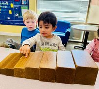 Preschool children at Level Up Montessori engaging in hands-on learning with wooden blocks.