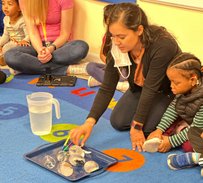 Montessori teacher engaging with children on a colorful carpet during an interactive lesson at a Bay Area center.