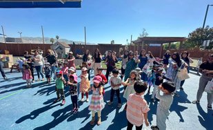 Children and adults participating in an outdoor Montessori learning activity to support confidence and kindergarten readiness.