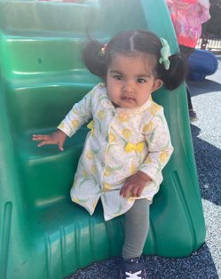 Infant sitting on a playground slide at Level Up Montessori, enjoying a nurturing and child-focused environment.