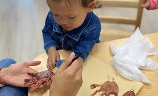 Infant creating handprint art at Level Up Montessori, supporting early growth and discovery.