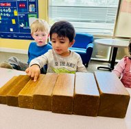 Preschool children at Level Up Montessori engaging in hands-on learning with wooden blocks.