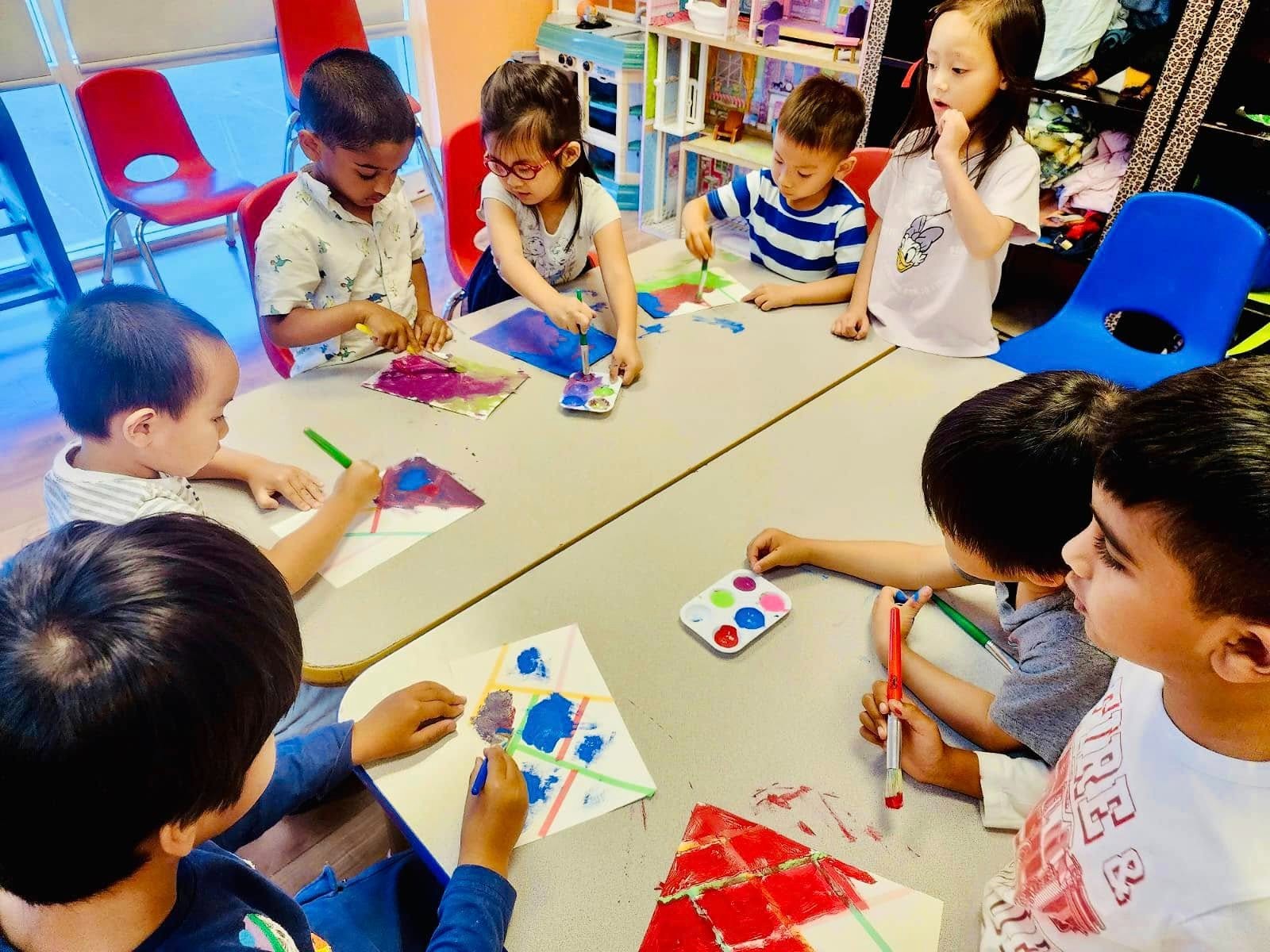 Toddlers engaged in hands-on learning at Level Up Montessori, painting with brushes and colors, building early skills.