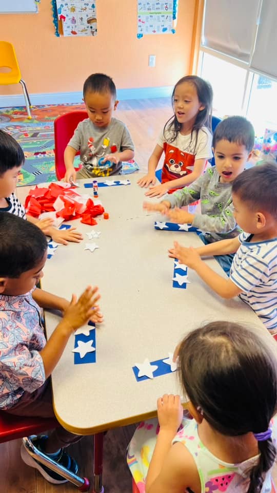 Toddlers at Level Up Montessori engaged in a hands-on learning activity around a table.
